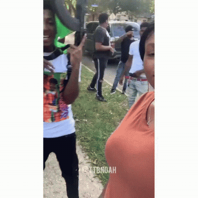 A Group Of People Are Standing On The Side Of The Road And One Of Them Is Giving The Peace Sign . GIF