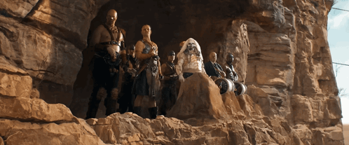 A Group Of People Are Standing On Top Of A Rock Formation GIF