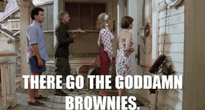 A Group Of People Are Standing Outside Of A House And A Man Is Holding A Tray Of Brownies . GIF