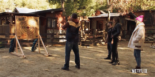 A Group Of People Are Throwing Axes At A Target That Says Golden Arrow GIF