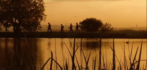 A Group Of People Are Walking Across A Lake At Sunset . GIF