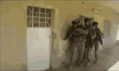 A Group Of People Are Walking Down A Hallway Holding Guns GIF