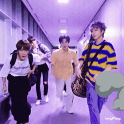 A Group Of People Are Walking Down A Hallway With A Dinosaur In The Background GIF