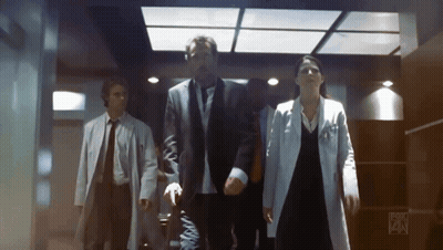 A Group Of People Are Walking Down A Hallway With Fox On The Bottom Right GIF
