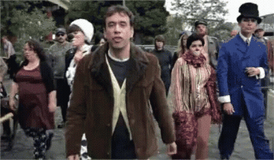 A Group Of People Are Walking Down A Street And One Man Is Wearing A Top Hat GIF
