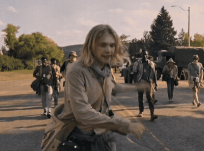 A Group Of People Are Walking Down A Street And One Of Them Has The Letter A On Their Shirt GIF