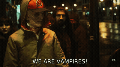 A Group Of People Are Walking Down A Street And They Are Vampires GIF