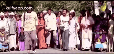 A Group Of People Are Walking Down A Street In A Crowded Area . GIF