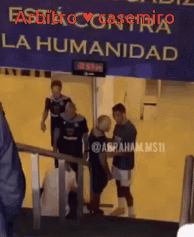 A Group Of People Are Walking Down Stairs Under A Sign That Says La Humanidad GIF