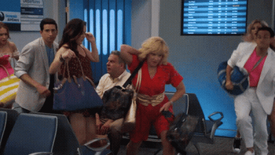 A Group Of People Are Walking In Front Of A Screen That Says Departures GIF