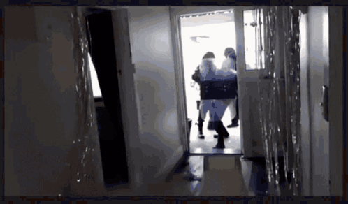 A Group Of People Are Walking Through A Hallway With A Silhouette Of A Person In The Background GIF