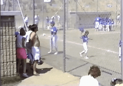 A Group Of People Are Watching A Baseball Game Behind A Chain Link Fence GIF