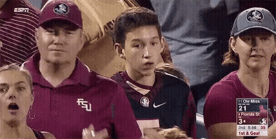 A Group Of People Are Watching A Football Game And One Of Them Is Wearing A Florida State Shirt GIF