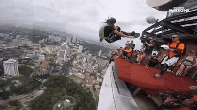 A Group Of People Are Watching A Person Jump Off A Building And The Words Awesome Are On The Bottom Right GIF