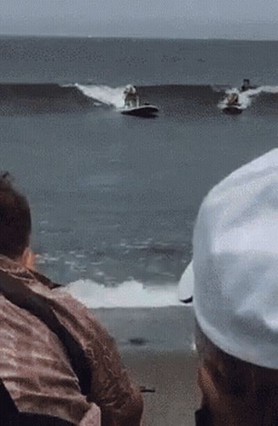 A Group Of People Are Watching Two Jet Skis Racing In The Ocean GIF