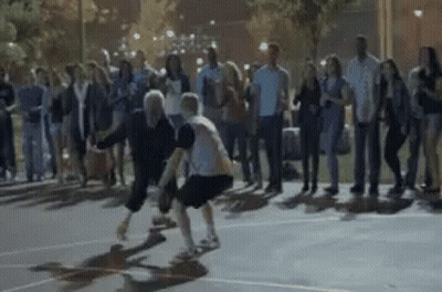 A Group Of People Are Watching Two People Play Basketball GIF