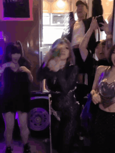 A Group Of People Dancing In A Dark Room With Purple Lights GIF