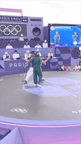 A Group Of People Dancing In Front Of A Paris 2024 Sign GIF