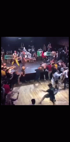 A Group Of People Dancing In Front Of A Sign That Says Artis On It GIF