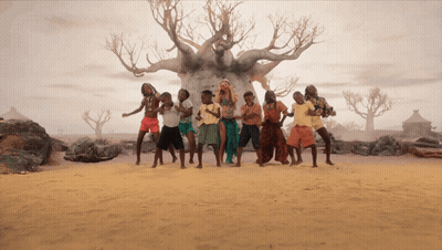 A Group Of People Dancing In Front Of A Tree In The Desert GIF