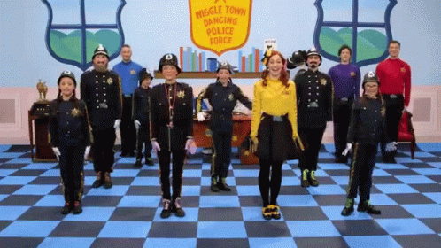 A Group Of People Dressed In Police Uniforms Are Standing In Front Of A Sign That Says Muggle Town Dancing Police Force GIF