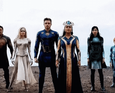 A Group Of People Dressed In Superhero Costumes Are Standing Next To Each Other On A Beach . GIF