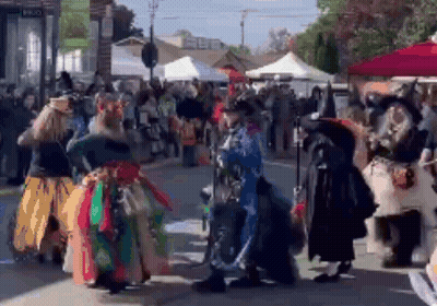 A Group Of People Dressed Up As Witches Are Dancing On A Street . GIF