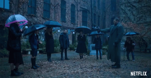A Group Of People Holding Umbrellas In Front Of A Building With Netflix Written On The Bottom GIF