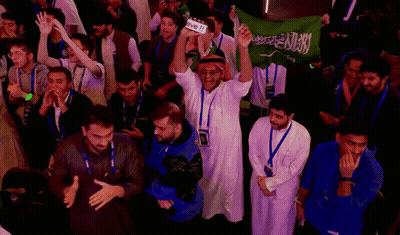 A Group Of People Holding Up A Green Flag With Arabic Writing GIF
