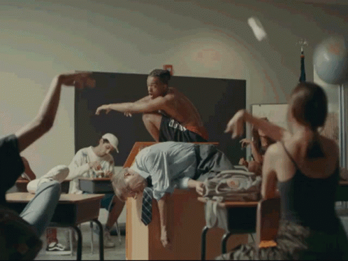 A Group Of People In A Classroom With One Wearing A Shirt That Says ' U.s.a. ' On It GIF