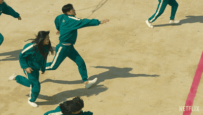 A Group Of People In Green Netflix Uniforms Are Running On A Dirt Field GIF