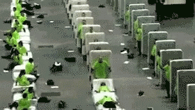 A Group Of People In Green Shirts Are Sitting In A Row Of Chairs . GIF