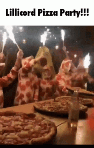 A Group Of People In Pepperoni Costumes Are Sitting At A Table With Pizzas And Sparklers . GIF