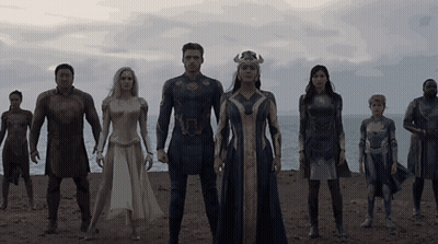 A Group Of People In Superhero Costumes Stand On A Beach GIF