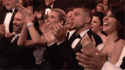 A Group Of People In Tuxedos Are Clapping Their Hands In A Crowd . GIF