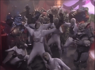 A Group Of People In White Jumpsuits Are Dancing GIF