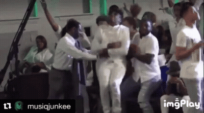 A Group Of People In White Shirts Are Dancing In A Room With A Green Light Behind Them . GIF
