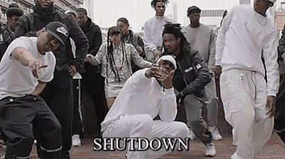 A Group Of People In White Shirts Are Dancing On A Sidewalk . GIF
