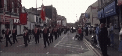 A Group Of People March Down A Street In Front Of A Kfc GIF