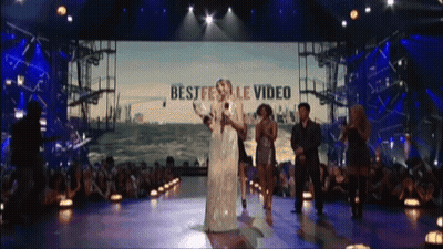 A Group Of People On A Stage With The Words Best Festival Video On The Screen Behind Them GIF