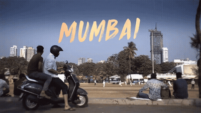 A Group Of People On Scooters In Front Of A Sign That Says ' Mumbai ' On It GIF