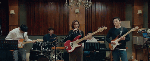 A Group Of People Playing Guitars And Singing In A Room GIF