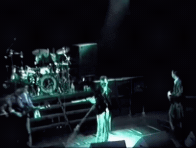 A Group Of People Playing Instruments On A Stage In A Dark Room . GIF