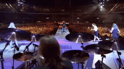 A Group Of People Playing Instruments On A Stage In Front Of A Crowd GIF