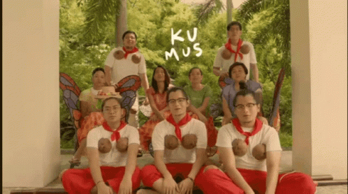 A Group Of People Posing For A Picture With The Words Ku Mus Written On The Wall Behind Them GIF
