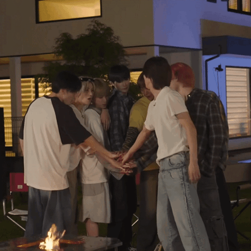 A Group Of People Putting Their Hands Together In Front Of A House GIF