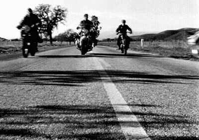 A Group Of People Riding Motorcycles Down A Road . GIF