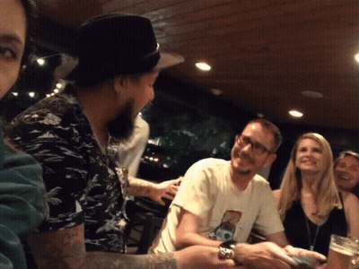 A Group Of People Sitting Around A Table With One Man Wearing A T-Shirt With A Picture Of A Dog GIF