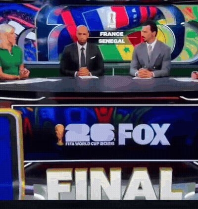 A Group Of People Sitting At A Table In Front Of A Sign That Says 26 Fox GIF