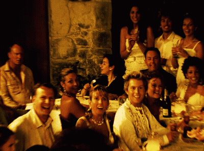 A Group Of People Sitting At A Table With A Bottle Of Wine On The Table GIF